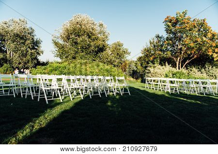 Place for wedding ceremony with white chairs and an arch of living plants