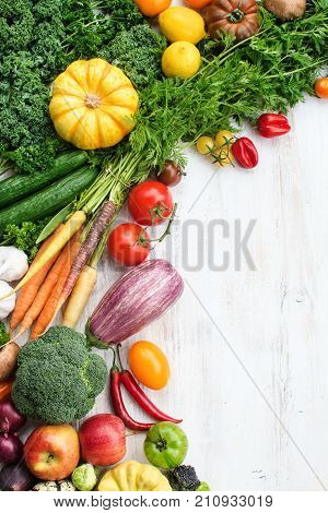 Top view of fresh raw vegetables, fruits and herbs on wooden white background, copy space for text, selective focus
