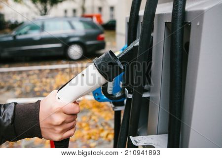 The driver picks up a cable to charge the electric vehicle. A modern and eco-friendly mode of transport that has become widespread in Europe. New technologies.