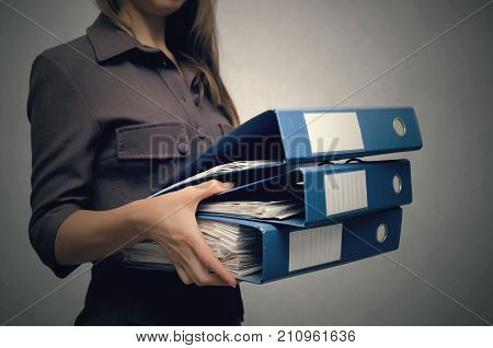Business woman holding a stack of folders for documents in front of her close up. Overworked woman concept. Documents work. Secretary.