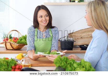Two young happy woman making cooking in the kitchen. Friendship and culinary concept.