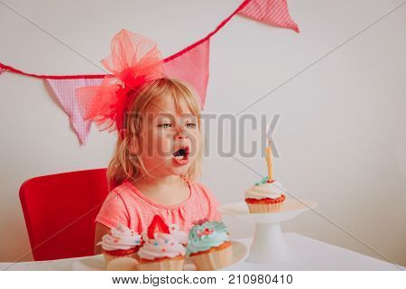 happy cute little girl make wish blow candles at birthday party