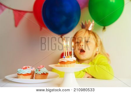 happy cute little girl make wish blow candles at birthday party