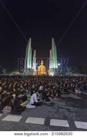 BANGKOK THAILAND - OCTOBER 26: Unidentified mourners in black sit and watch the royal activities for the cremation of Rama 9 the former king next to Democracy Monument in Bangkok Thailand on October 26 2017.