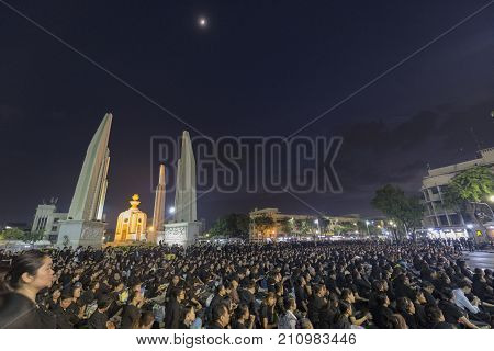 BANGKOK THAILAND - OCTOBER 26: Unidentified mourners in black sit and watch the royal activities for the cremation of Rama 9 the former king next to Democracy Monument in Bangkok Thailand on October 26 2017.