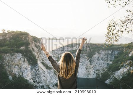 Woman arms raised and holding flag on mountain