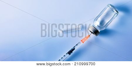Vial With Punctured Syringe Close Up With Blue Background
