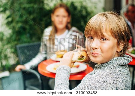 Family Having Lunch Outside On A Terrace, Background With Meal, Children Eating Humburgers