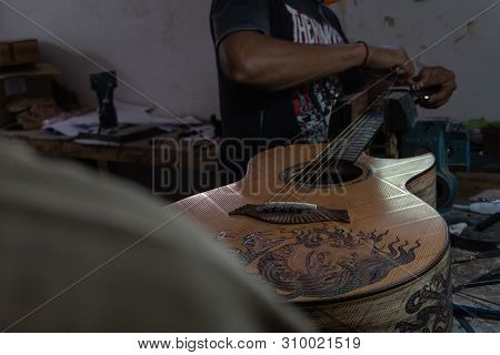 Gianyar,bali/indonesia-may 30 2019: A Classical Guitar Craftsman Is Pairing Guitar Strings To His Gu