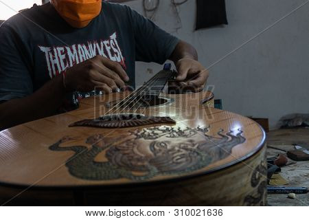 Gianyar,bali/indonesia-may 30 2019: A Classical Guitar Craftsman Is Pairing Guitar Strings To His Gu