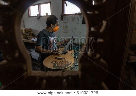 Gianyar,bali/indonesia-may 30 2019: A Classical Guitar Craftsman Is Pairing Guitar Strings To His Gu