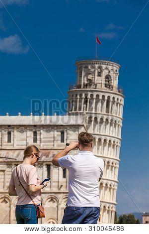 Pisa, Italy - April, 2018: Young Couple Of Tourists Taking Pictures Of The Famous Leaning Tower Of P
