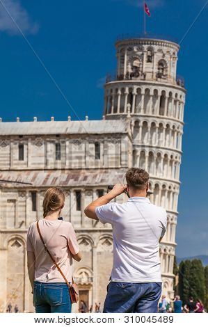 Pisa, Italy - April, 2018: Young Couple Of Tourists Taking Pictures Of The Famous Leaning Tower Of P