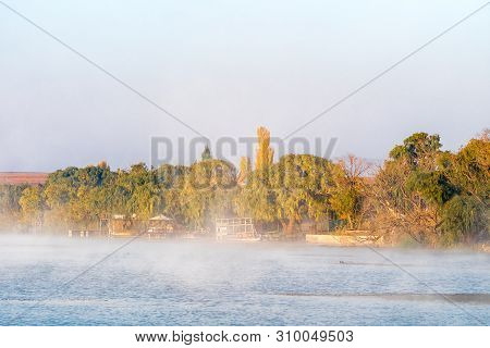 Vrede, South Africa - May 2, 2019: Boats And Piers Are Visible Through The Mist At Sunrise On The Da