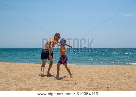 Father And Son On The Beach On A Clear Day. People Have Fun In The Fresh Air. The Concept Of A Summe