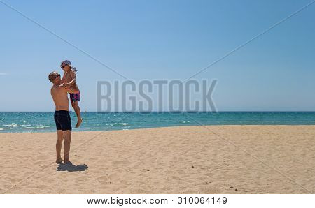 Father And Son On The Beach On A Clear Day. People Have Fun In The Fresh Air. The Concept Of A Summe