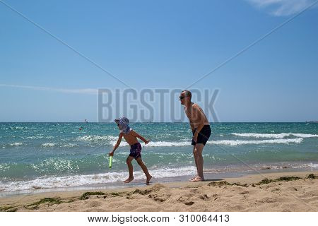 Father And Son On The Beach On A Clear Day. People Have Fun In The Fresh Air. The Concept Of A Summe