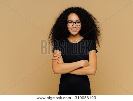 Slim Satisfied Woman With Afro Haircut, Wears Black Casual Clothes, Optical Glasses, Has Confident E