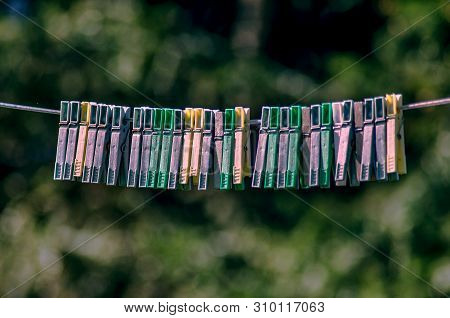 Plastic Clothes Pins Hanging On String Rope. Colorful Laundry Pins Hanging On A Clothesline. The Peg