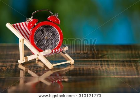 Chaise Lounge On A Wet Wooden Board, In A Chaise Lounge There Is A Red Alarm Clock, Concept Of Rest