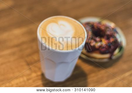 Coffee With A Heart Made Of Milk And A Donut On A Wooden Table. Bad Breakfast. Coffee With A Drawn H