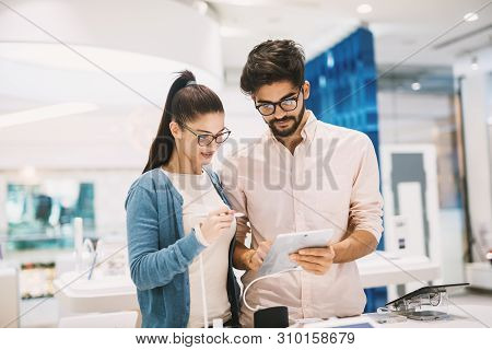 Attractive Young Couple Looking At An Electric Drawing Board In The Big Tech Shop.