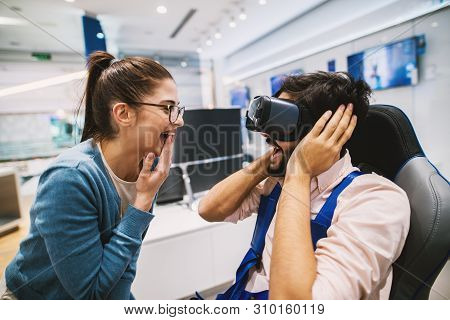 Hipster Young Modern Couple Checking Out Vr Goggles In The Tech Store.