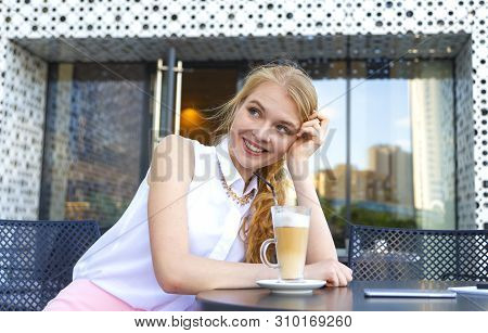 Young Smiling Woman Having Coffee Break Sitting At Cafe And Drinking Latte Through Straw. Fashionabl