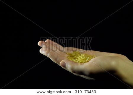 Close-up Of Human Fingers Move A Handful Of Vermicell In Hand On A Black Background, Unrecognizable 