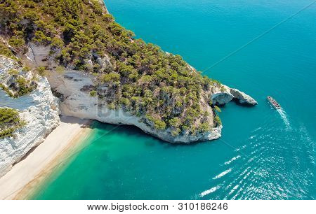 Aerial View Of A Boat With Tourists Visiting A Groat Puglia Coast, Italy. Italian Holidays In Puglia