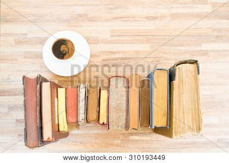 Books Row On Wooden Table With White Cup Of Coffee, Top View Flat Lay. Reading, Learning, Literature