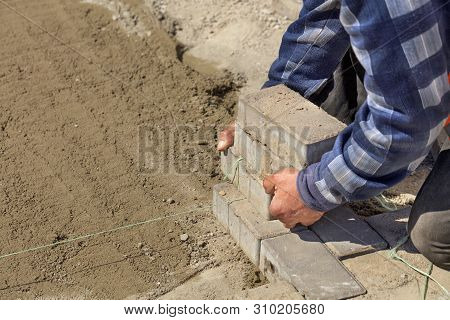 A Worker Puts On A Nylon Cord For The Subsequent Laying Of Paving Slabs On The Prepared Flat Sandy P