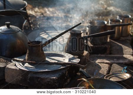 Close-up Of A Few Smoked Cezva On Campfire For Coffee, A Kettle And A Frying Pan, A Concept Of Cooki