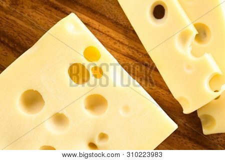 Piece And Slices Of Emmental, Emmentaler Or Emmenthal Cheese, Photographed Overhead On Wood