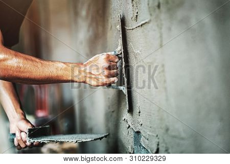 Closeup Hand Of Worker Plastering Cement At Wall For Building House