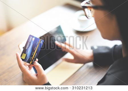 Woman Hands Holding Credit Card And Using Tablet For Online Shopping In A Office Table Coffee Cup Ba