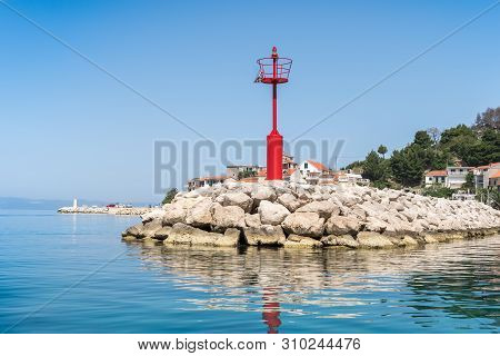 Red Lighthouse In Podgora Village And Adriatic Sea Bay, Croatia