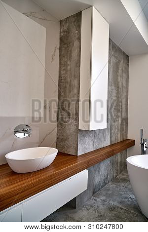 Luxury bathroom vanity. Ceramic round sinks placed on teak tabletop in luxury bathroom with gray and white marble walls