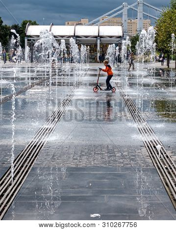 Moscow,museon Park,september 4,2016: Boy Fun Riding A Scooter Between The Jets Of Water In The Fount