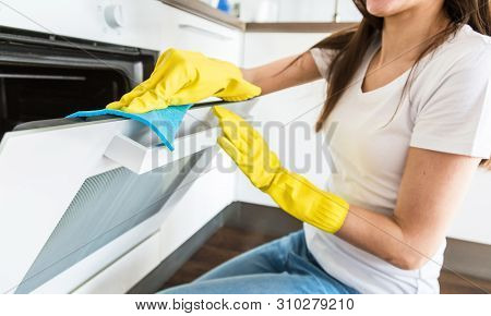 A Young Woman From A Professional Cleaning Company Cleans Up At Home. A Man Washes The Kitchen In Ye