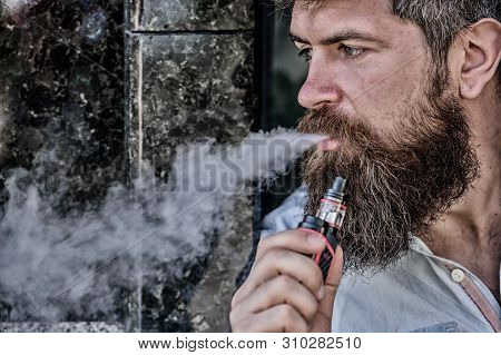 Man With Beard Breathe Out Smoke. Smoking Electronic Cigarette. Stress Relief Concept. Smoking Devic