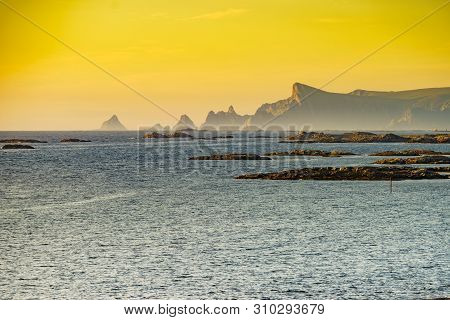 Seascape On Andoya Island. Scenic Rocky Coastline With Mountain Peaks In Distance, View From Bukkekj