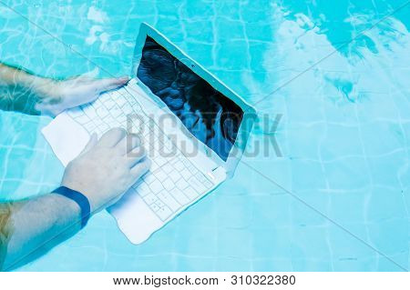 Male Works On Minicomputer Under Water. Minicomputer At The Bottom Of The Pool. The Concept Of A Lot