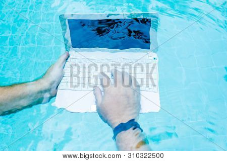 Male Works On Minicomputer Under Water. Minicomputer At The Bottom Of The Pool. The Concept Of A Lot