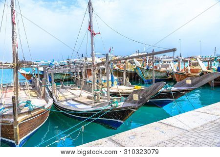 Al Khor, Qatar - February 23, 2019: Fishing Boats Or Traditional Wooden Dhows Docked At Harbor Of Al