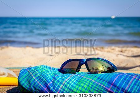 Diving Mask, Snorkel, Sung Lasses And Blue Plaid Dress Are Placed On Mat At The Sandy Beach.