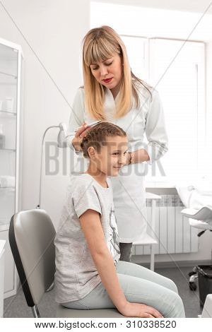 Doctor Trichologist Examines The Hair Of A Little Girl Patient In His Office.