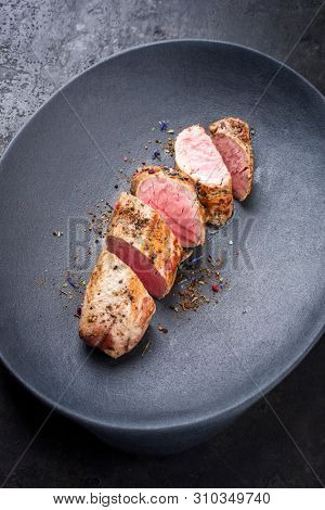 Fried Iberian pork fillet sliced with spice as closeup in a cast iron design plate 