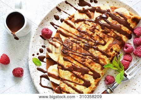 Crepe With Chocolate Paste, Banana And Raspberries On A Concrete Background. Tasty Breakfast.