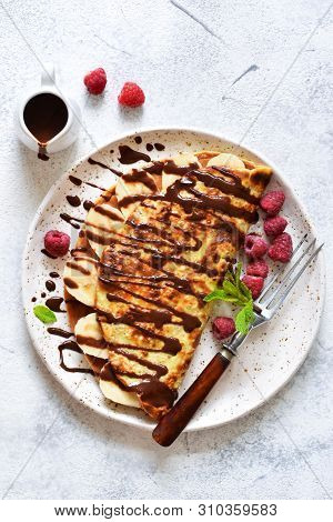 Crepe With Chocolate Paste, Banana And Raspberries On A Concrete Background. Tasty Breakfast.